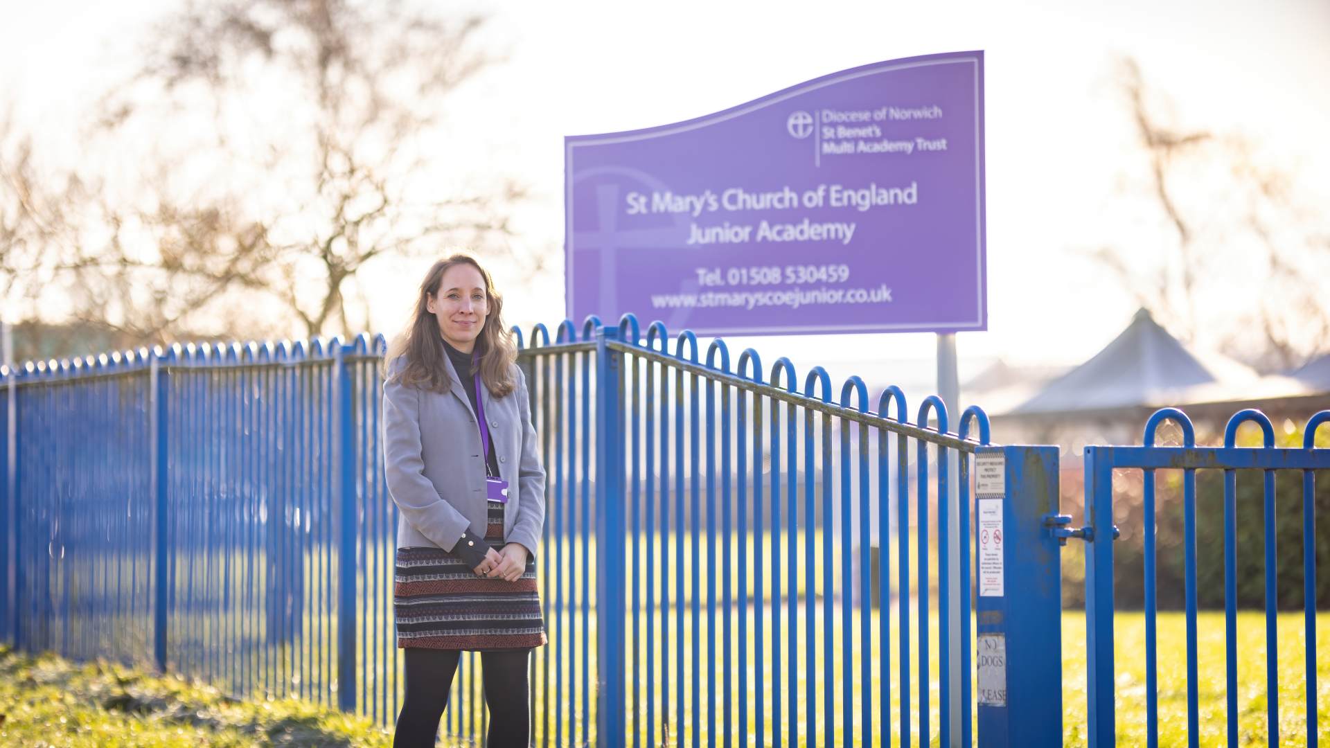 Laura outside her school, St Mary's Junior Academy A woman stands in front of a school sign
